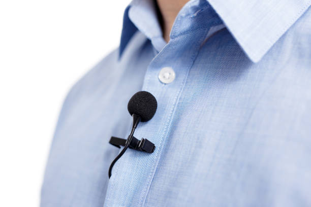 sound recording and broadcasting concept - close up of small lavalier clip-on microphone on male shirt